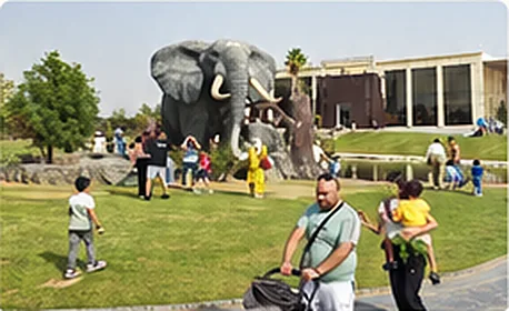Families on the lawn beside a large elephant statue.